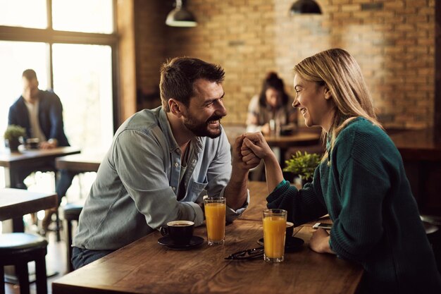 手をつないで、カフェで話している幸せなカップル