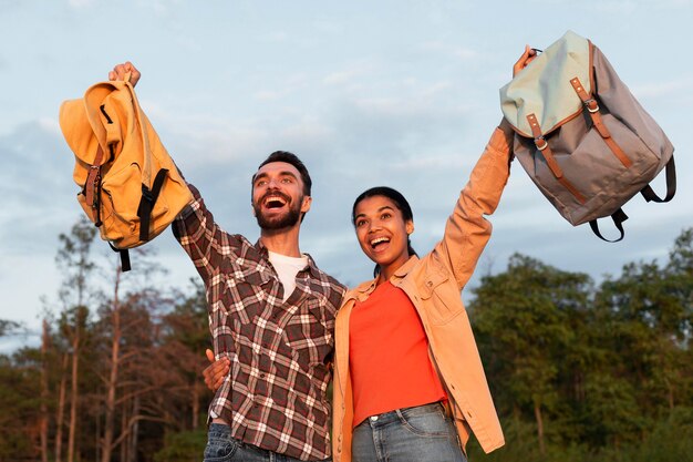 Happy couple holding their backpaks up