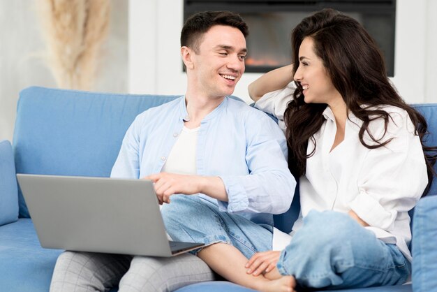 Happy couple at home on sofa with laptop
