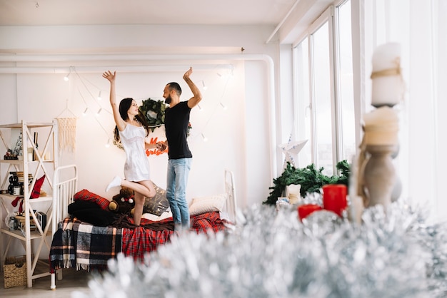 Happy couple jumping on bed