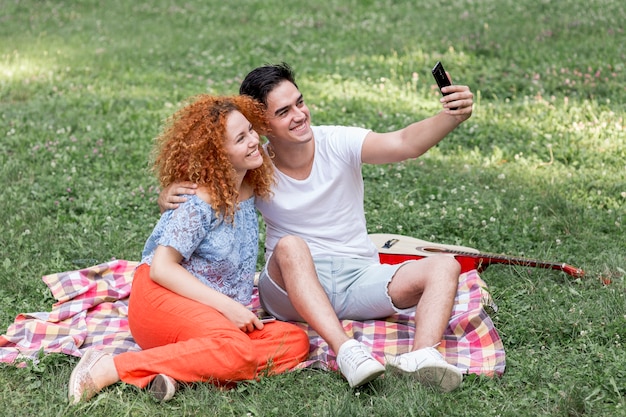 행복 한 부부는 selfie를 복용하는 잔디에 누워