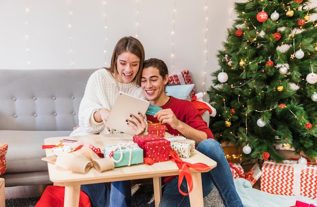 Free photo happy couple looking at tablet on couch