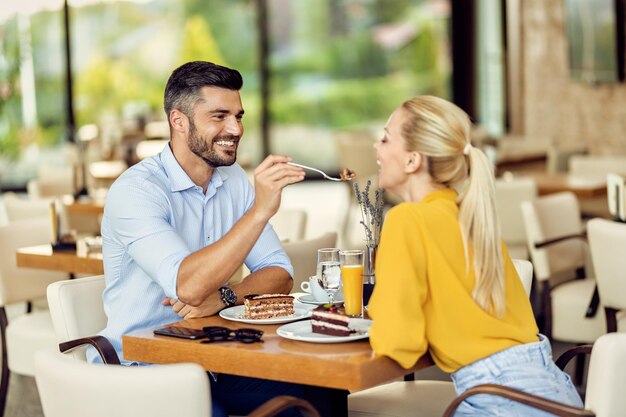 Happy couple in love sharing dessert in a cafe