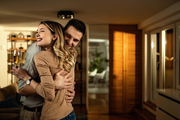 Happy couple in love standing embraced in the living room at night