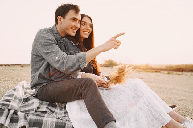 Happy couple in love in wheat field at sunset