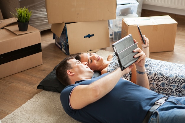 Free photo happy couple lying on the floor after moving in .woman and man smiling