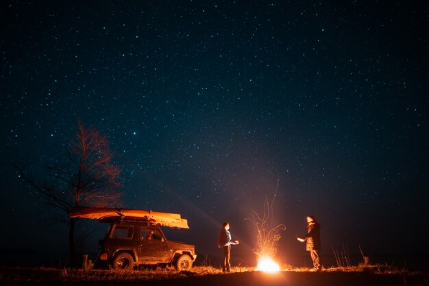 Happy couple man and woman standing in front burning bonfire