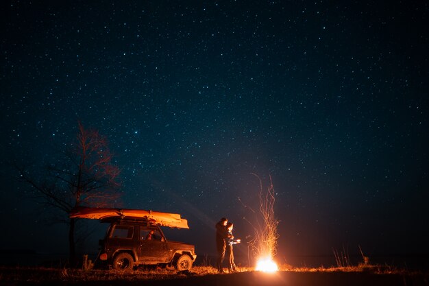 Happy couple man and woman standing in front burning bonfire