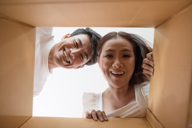 Free photo happy couple opening a box and looking inside to product