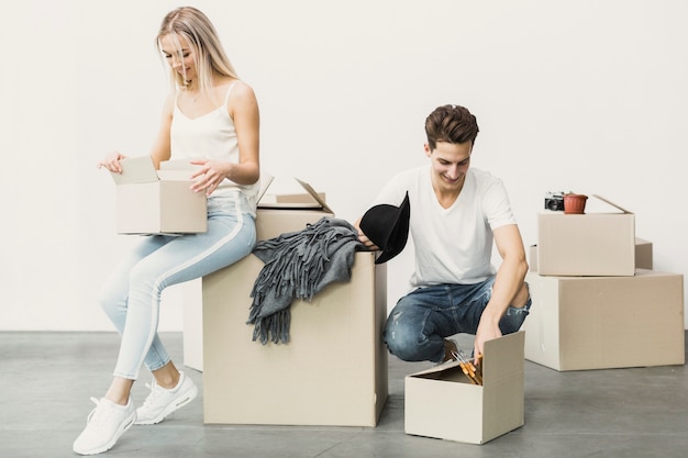 Free photo happy couple packing clothes in boxes