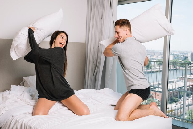 Happy couple playing pillow fight on bed