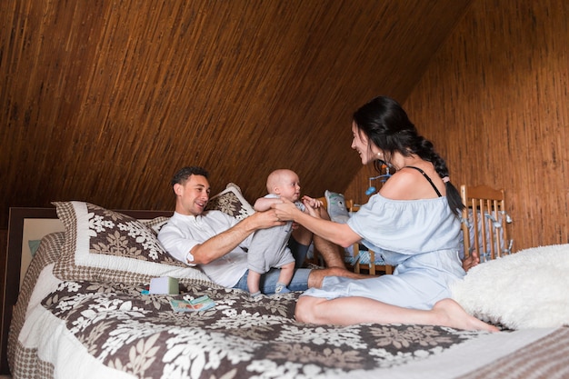 Happy couple playing with baby on bed at home