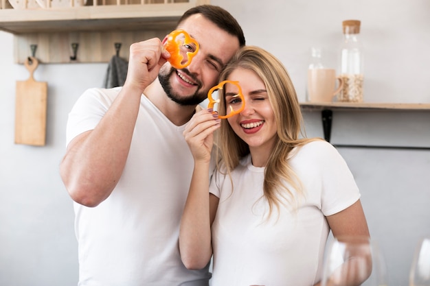 Free photo happy couple playing with bell pepper