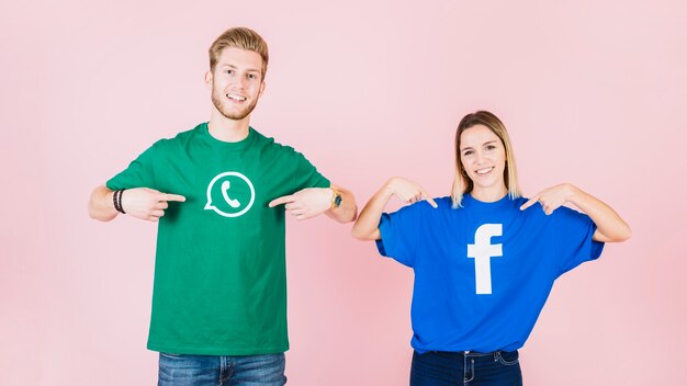 Happy couple pointing at their t-shirt with facebook and whatsapp icon