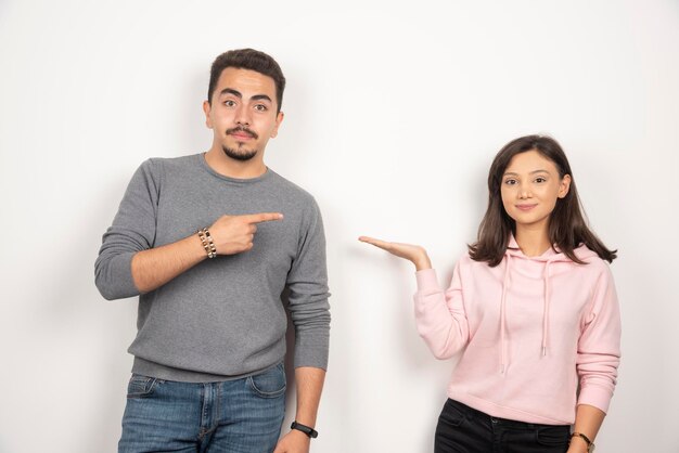 Happy couple pointing at themselves on white.