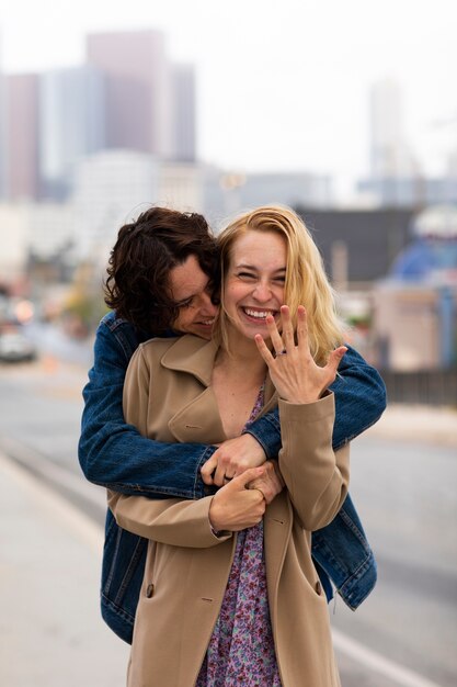 Happy couple posing outdoors in the city with engagement ring