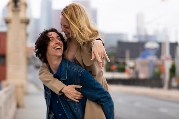 Happy couple posing outdoors in the city with engagement ring