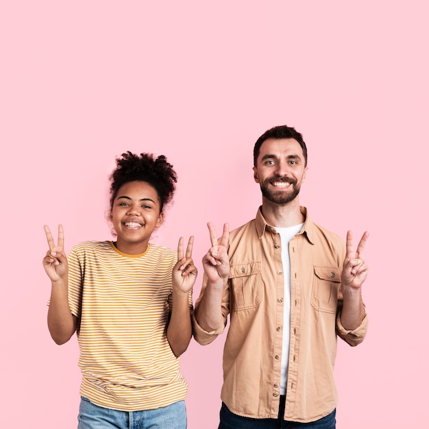 Free photo happy couple posing with peace sign