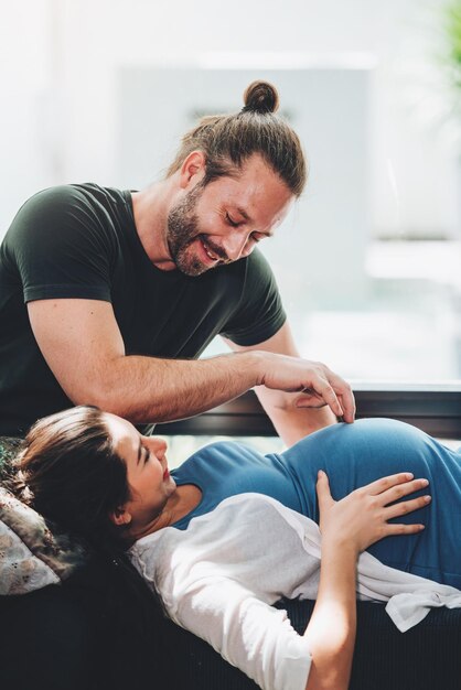 幸せなカップルの妊娠中の女性と夫は居間に家にいる幸せなカップルは一緒に世話をします