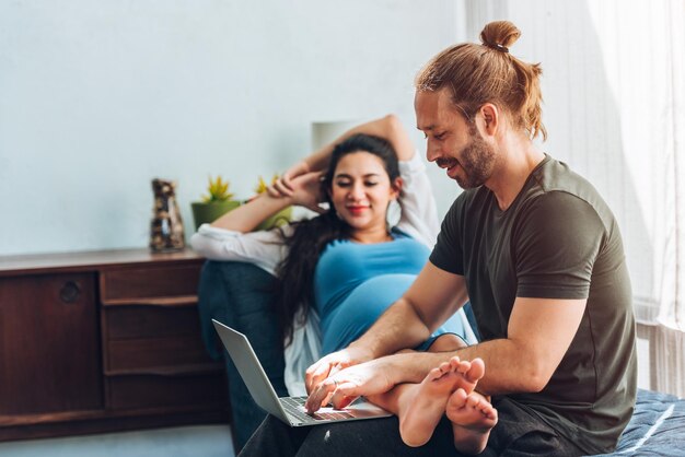 Happy couple pregnant woman and husband stay home in living room Happy couple taking care together