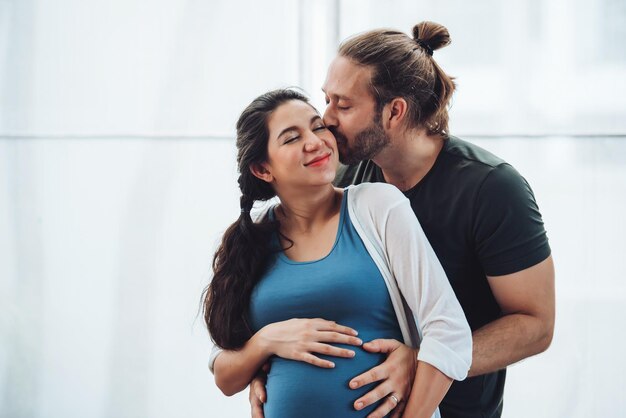 幸せなカップルの妊娠中の女性と夫は居間に家にいる幸せなカップルは一緒に世話をします