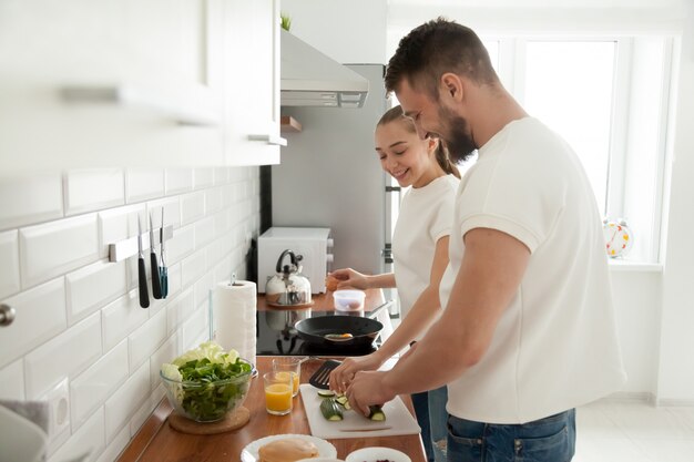 happy couple preparing breakfast together in kitchen in morning