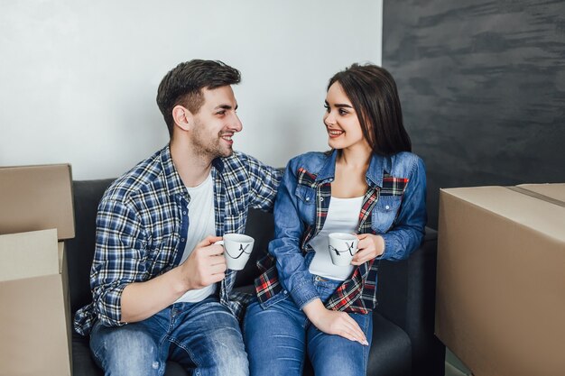 Счастливая пара отдыхает на диване с кофе в новой квартире