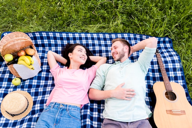 Free photo happy couple resting on picnic plaid