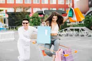 Free photo happy couple riding shopping cart