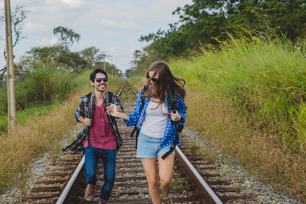 Free photo happy couple running on train tracks