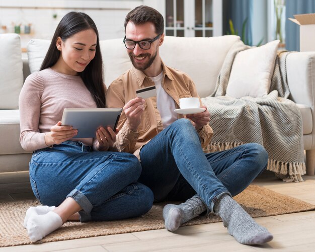 Happy couple shopping online on tablet using credit card