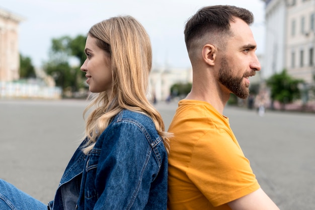 Free photo happy couple sitting back to back