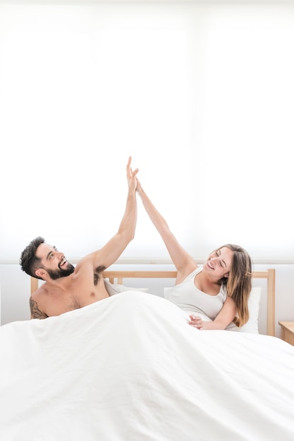 Happy couple sitting on bed giving high five