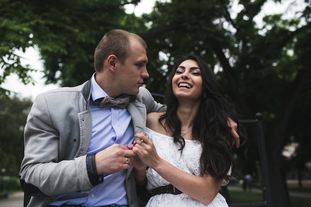 Free photo happy couple sitting on a bench in the park