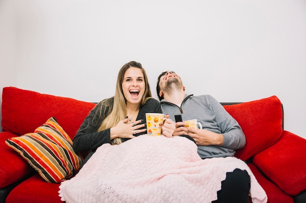 Happy couple sitting on sofa enjoying movie