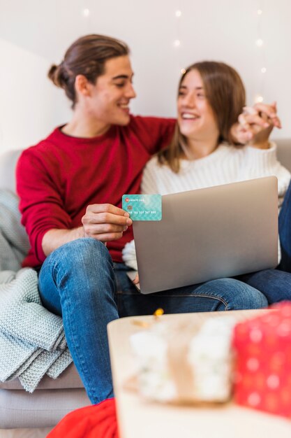 Happy couple sitting with laptop on couch 