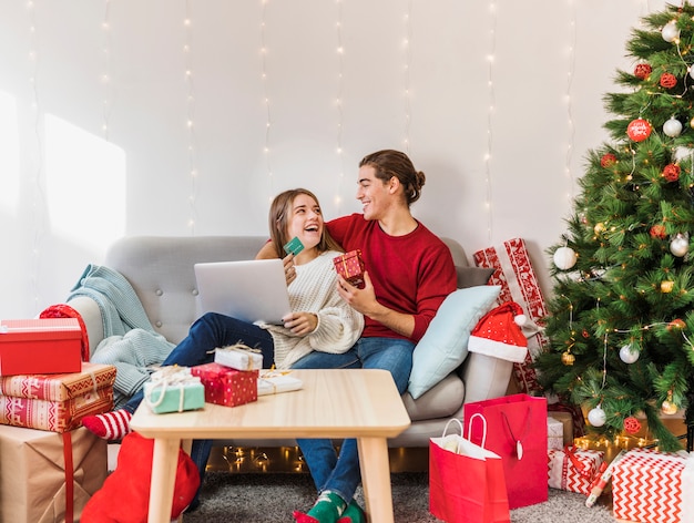 Happy couple sitting with laptop and credit card on couch