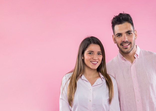 Happy couple standing on pink background 