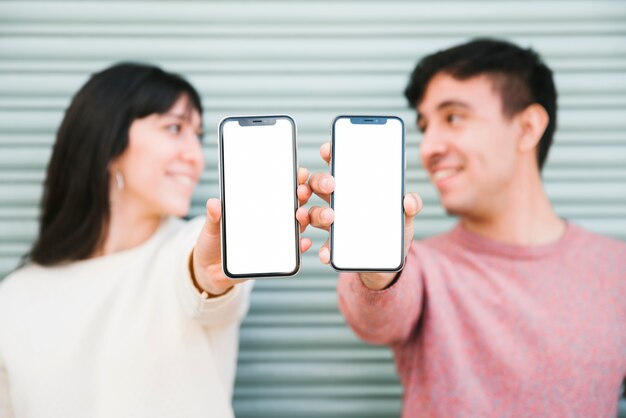 Happy couple standing with smartphones