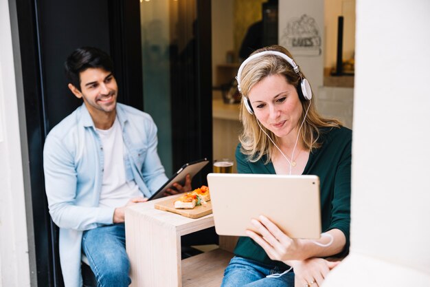 Happy couple staying in cafeteria using tablets