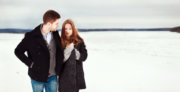 Happy couple strolling along the snowy meadow