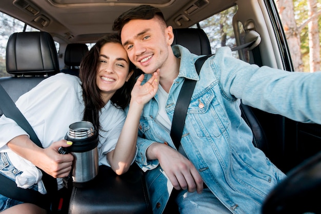 Happy couple taking selfie in car