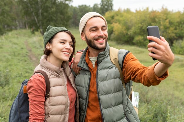 スマートフォンで自然の中で自分撮りを撮る幸せなカップル