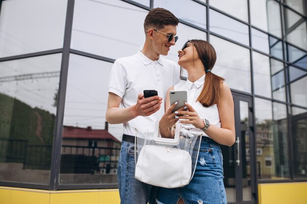 Happy couple together out in the city using phone