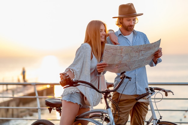 счастливая пара путешествует летом на велосипедах, глядя на карту достопримечательностей