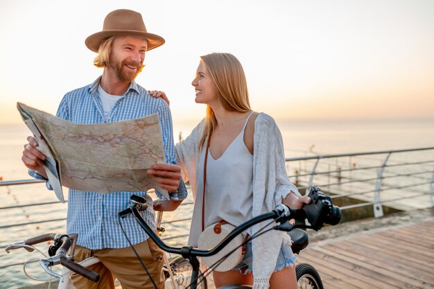 счастливая пара путешествует летом на велосипедах, глядя на карту достопримечательностей