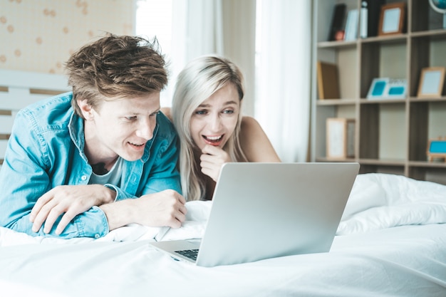 Happy couple Using laptop computer on the bed