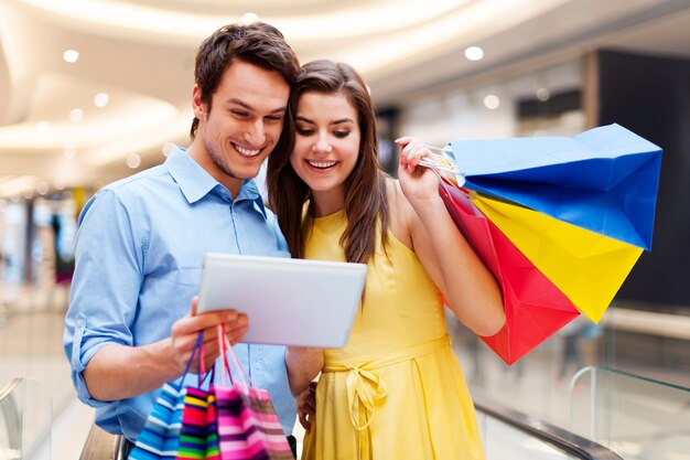 Happy couple using s digital tablet in the shopping mall