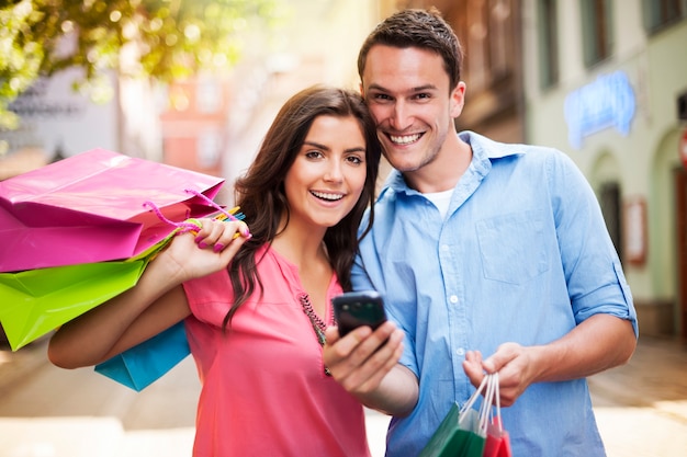 쇼핑하는 동안 스마트 폰을 사용 하여 행복 한 커플