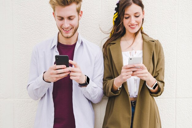 Happy couple using smartphone outdoors